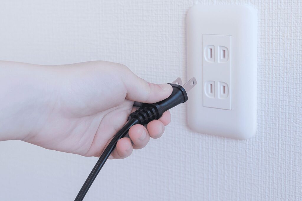 コンセントに電源プラグを指している人のイメージ画像